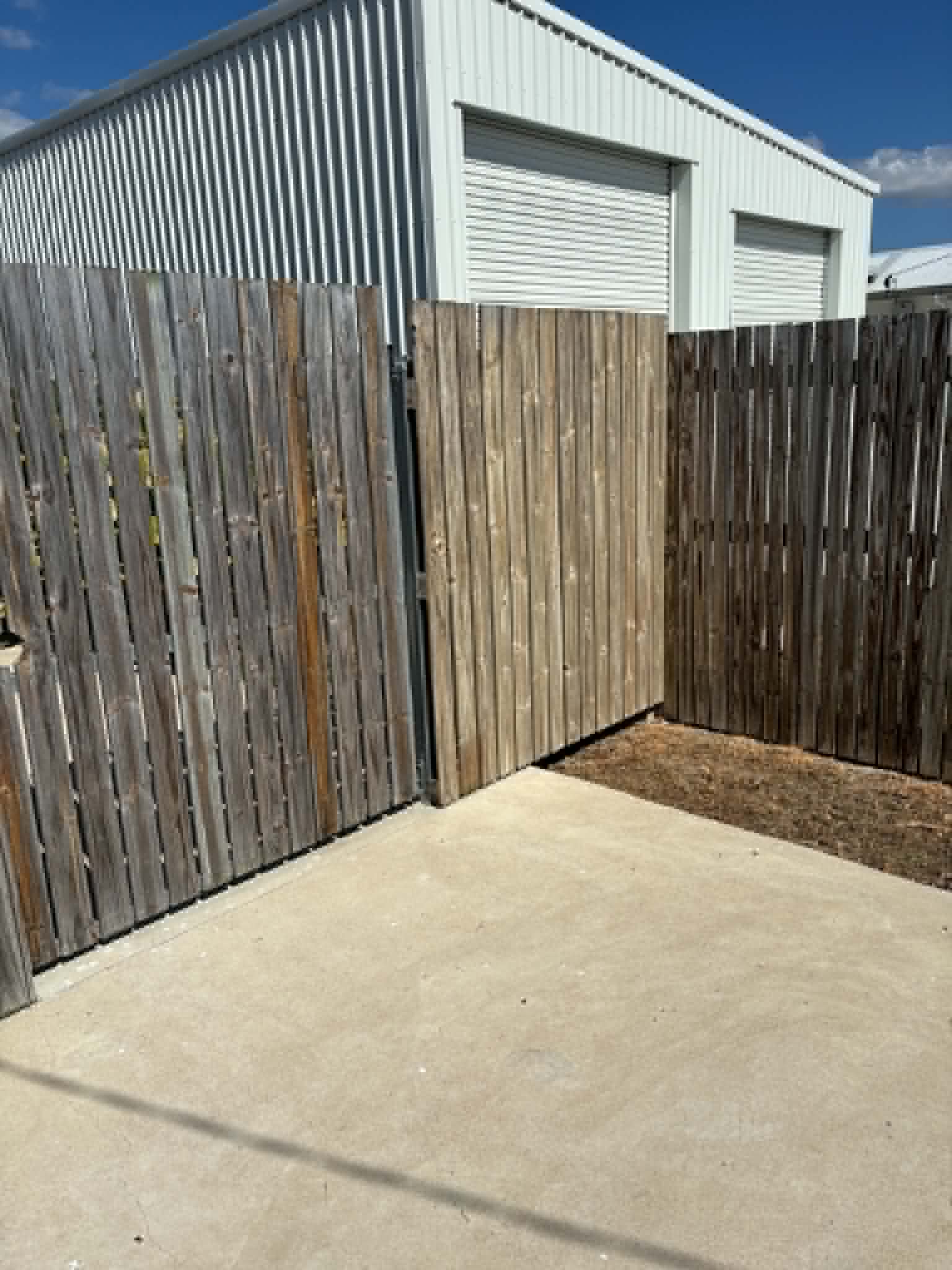 Fence panel cleaned, showing clean timber next to weathered grey panels